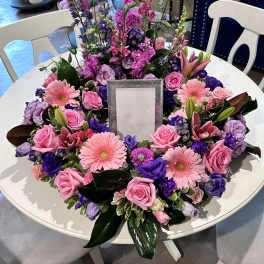 Round floral wreath with pink and purple blooms around a center frame