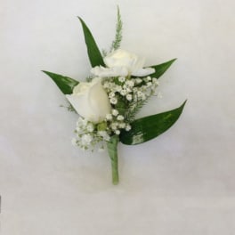 White rose boutonniere with baby's breath and green leaves