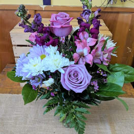 Lavender roses with white daisies and pink-purple blooms in a vase