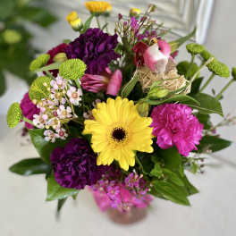 Mixed bouquet with yellow gerbera, purple carnations, and a small bird decoration