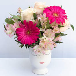 Pink gerbera daisies and pale roses in a white vase