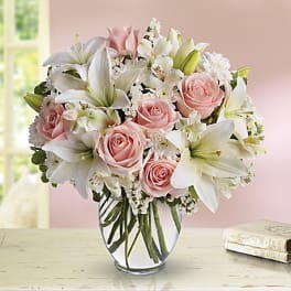 Pink roses and white lilies arranged in a clear glass vase