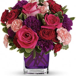 Bouquet of pink, red, and purple flowers in a purple glass vase