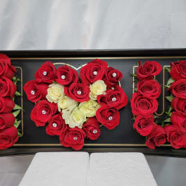 Red and white roses arranged in a black display box spelling "MOM"