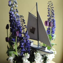 Sailboat-shaped floral arrangement with purple and white flowers