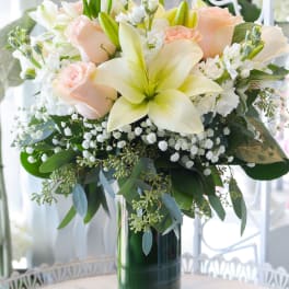 Bouquet of pale roses and lilies in a tall glass vase