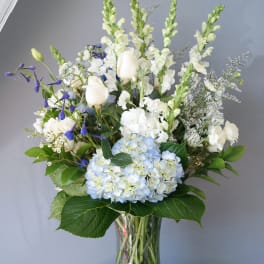 White and blue floral arrangement in a glass vase