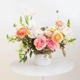 Pink and peach flower arrangement in a white container