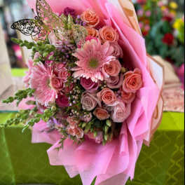 Pink bouquet of roses and gerbera daisies wrapped in pink paper