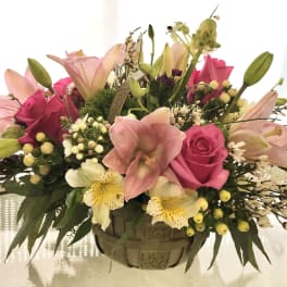 Pink lilies and roses arranged in a woven basket