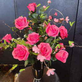 Pink roses arranged in a black vase with small pink blossoms