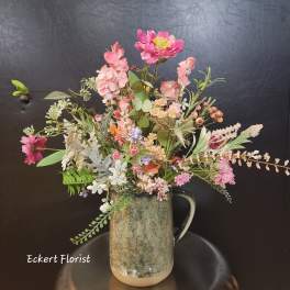 Mixed pink floral arrangement in a ceramic pitcher vase