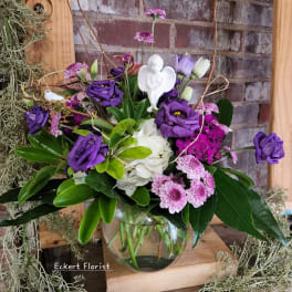 Purple and white flowers arranged in a clear glass vase