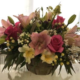 Pink lilies and roses in a basket arrangement