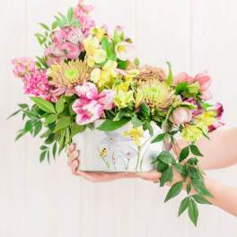 Pink and yellow mixed bouquet in a decorative tin container