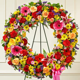 Colorful floral wreath on a black easel with a pink ribbon