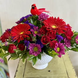 Red and purple mixed bouquet in a white vase with a red bird decoration