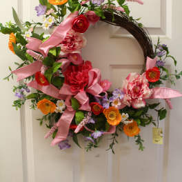 Floral wreath with pink ribbon and mixed orange, red, purple, and pink flowers