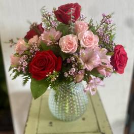 Bouquet of red and pink roses in a textured glass vase