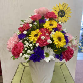 Colorful mixed bouquet in a white vase with daisies and carnations