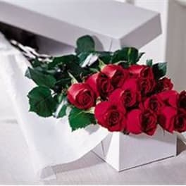 Bouquet of red roses with dark green foliage in a white box