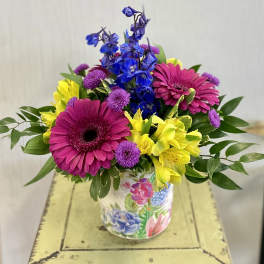 Bright mixed bouquet in a floral tin container