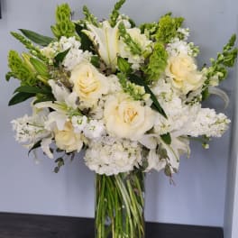 Cream roses and white lilies in a tall glass vase