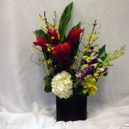 Tropical floral arrangement with red and purple blooms in a black vase
