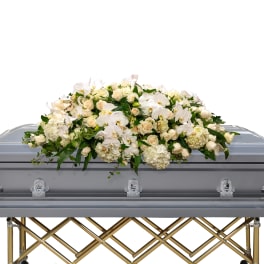 White floral casket spray on a gray casket