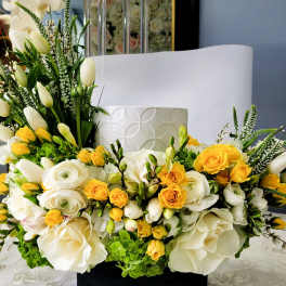 White and yellow floral arrangement with roses and tulips in a white vase
