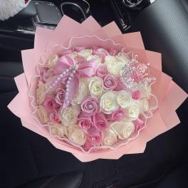 Pink and white rose bouquet wrapped in pink paper with pearl accents