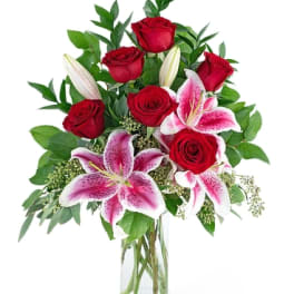 Red roses and pink lilies arranged in a clear glass vase