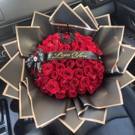 Bouquet of red roses wrapped in black paper with gold trim