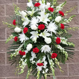 Standing funeral spray with white lilies, chrysanthemums, and red carnations