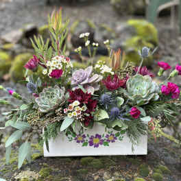 Succulent and magenta flower arrangement in a painted wooden box