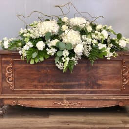 White floral arrangement on a wooden chest with curly branches