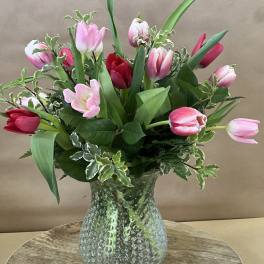 Pink and red tulips arranged in a textured glass vase