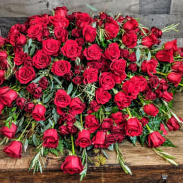 Large mound of red roses arranged in a low cascading display on a wooden surface