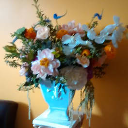 Mixed floral arrangement in a blue vase on a pedestal