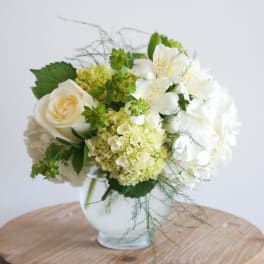 White and pale green floral arrangement in a glass vase