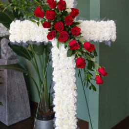 White floral cross with red roses on a stand