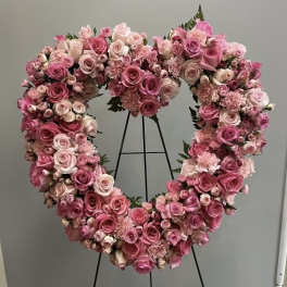 Heart-shaped floral wreath of pink and blush roses on a stand