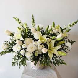 White lilies and roses arranged in a white basket