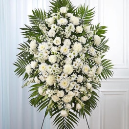 Large white funeral spray with mixed blooms and palm fronds
