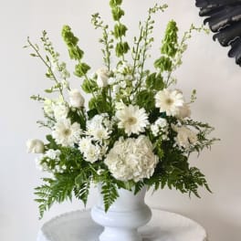 White floral arrangement in a white pedestal vase