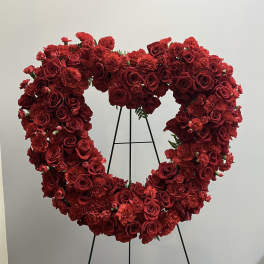 Heart-shaped red rose and carnation floral wreath on a stand