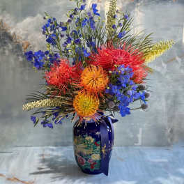 Colorful floral arrangement in a blue vase with a ribbon