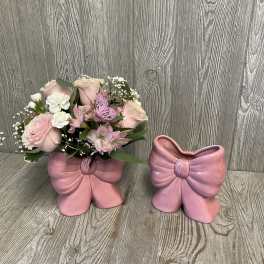 Pink and white flower arrangement in a pink bow-shaped vase beside an empty matching vase