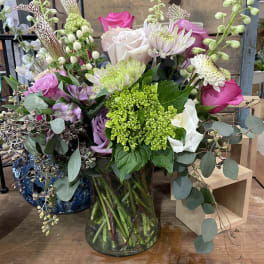 Mixed bouquet of pink, white, and green flowers in a glass vase