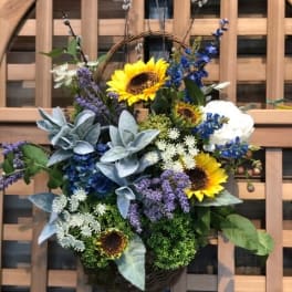 Basket arrangement with sunflowers, blue flowers, and white blooms
